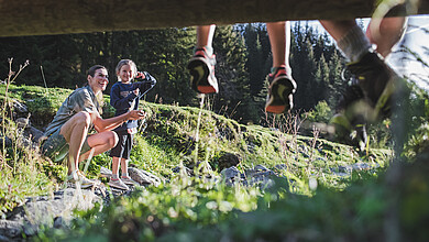 Family exploring on the riverbank, Saalbach Hinterglemm valley head