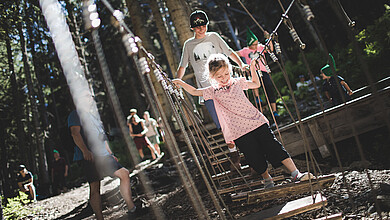 Brother and sister doing parcour at the Baumzipfelweg treetop trail in Saalbach Hinterglemm
